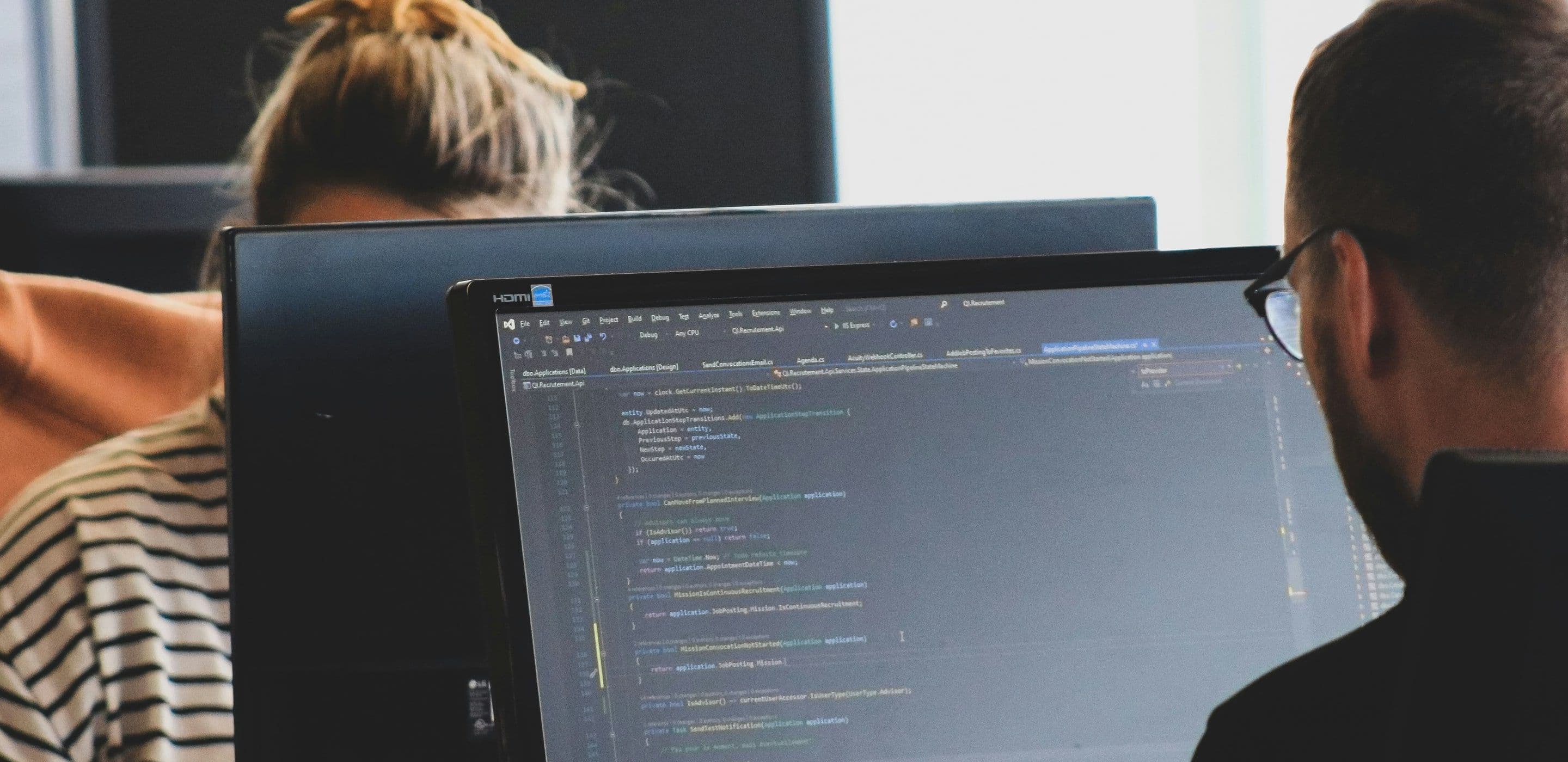 Two developers at a monitor full of code