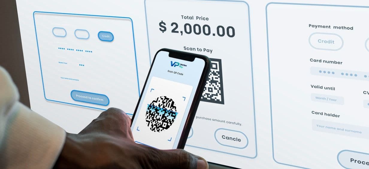 A hand holding a phone up to scan a QR code on a payment screen