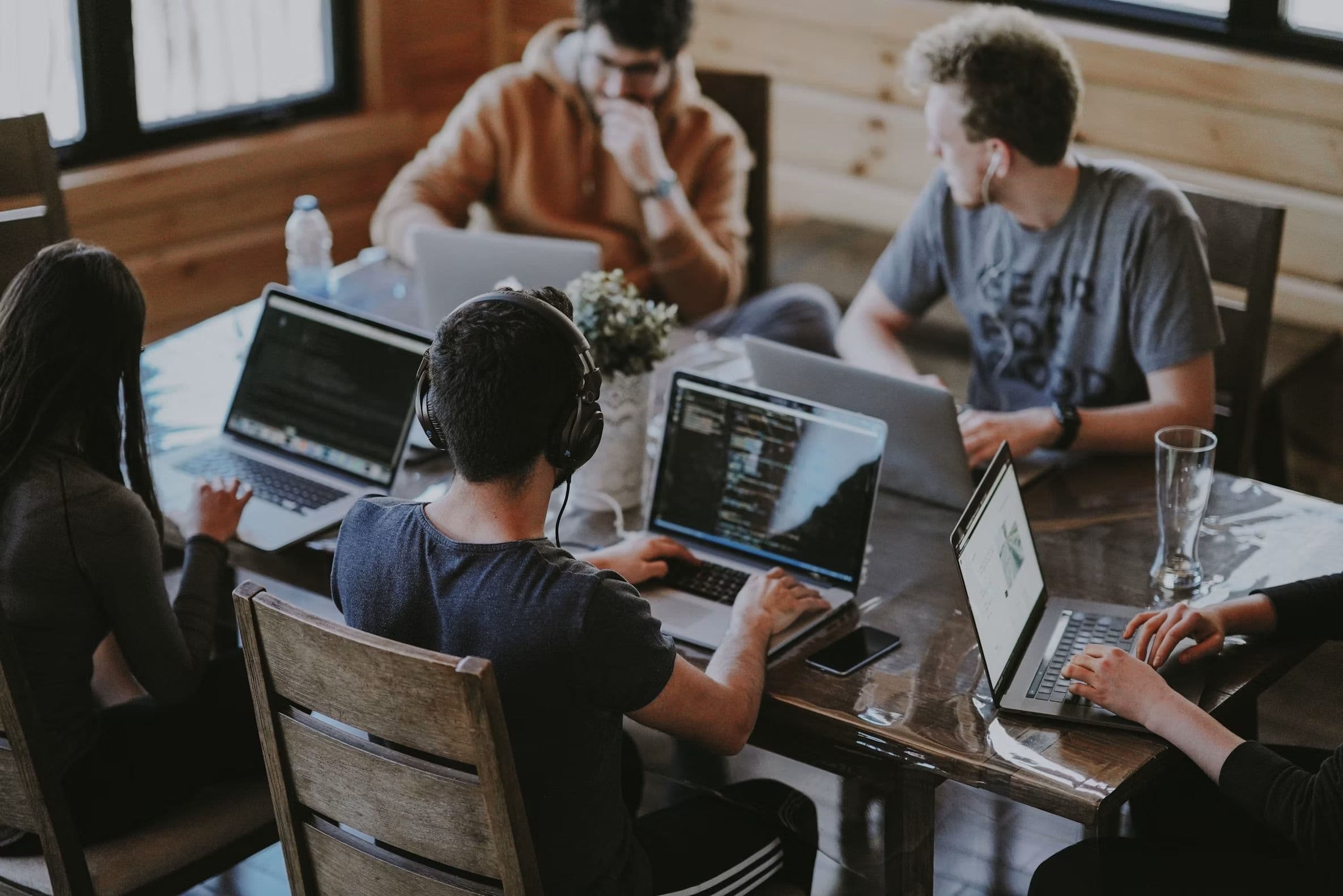 A team working on laptops around a wooden table